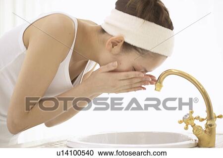 Stock Image - Young woman washing face. Fotosearch