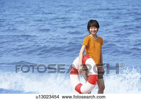 Picture - Young woman with inner tube on beach, Toyama Prefecture, Honshu, Japan. Fotosearch