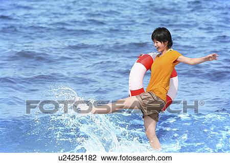 Stock Image - Young woman with inner tube on beach, Toyama Prefecture, Honshu, Japan. Fotosearch