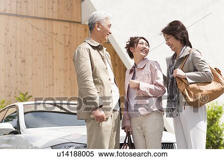 Stock Photography - Young woman with parents standing by car, smiling. Fotosearch