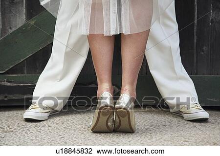 Stock Image - a bride standing on her tip toes in front of a groom. Fotosearch