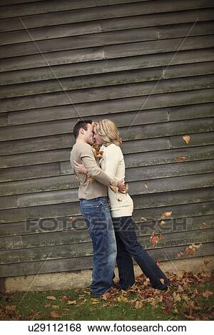 Stock Photo - a couple standing in the autumn leaves and kissing. Fotosearch
