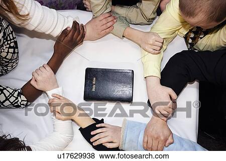 a group of people praying around a bible View Large Photo Image Stock Photo - a group of people praying around a bible. Fotosearch