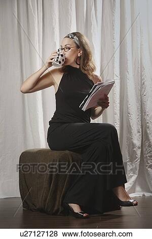 a woman drinking from her mug and holding a document View Large Photo Image Stock Photo - a woman drinking from her mug and holding a document. Fotosearch