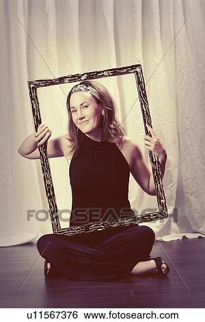 Stock Photograph - a woman holding a picture frame around her face and torso. Fotosearch