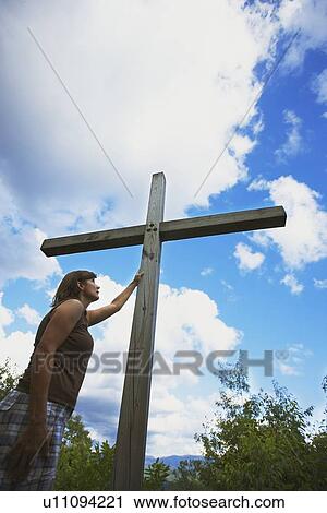 Stock Image - a woman touches the cross. Fotosearch