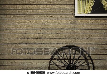 Stock Photograph - alberta, canada; an old wagon wheel leaning against a house. Fotosearch