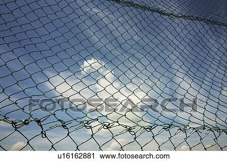 Stock Image - alberta, canada; the sky through a chain link fence. Fotosearch