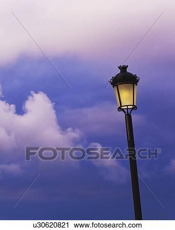 an illuminated lamp post against a cloudy sky View Large Photo Image Stock Image - an illuminated lamp post against a cloudy sky. Fotosearch