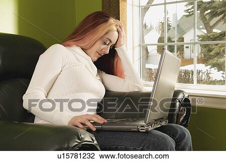 Stock Image - edmonton, alberta, canada; a young woman dozing with a laptop computer on her lap. Fotosearch