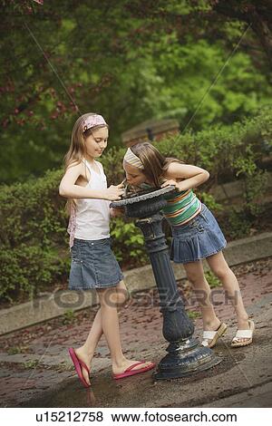 Stock Photo - edmonton, alberta, canada; two girls at a drinking fountain. Fotosearch