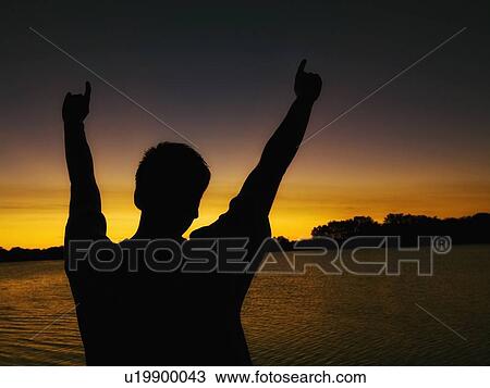 willmar, minnesota, united states of america; silhouette of a man with his arms raised as he watches the sunset over a lake View Large Photo Image Stock Image - willmar, minnesota, united states of america; silhouette of a man with his arms raised as he watches the sunset over a lake. Fotosearch