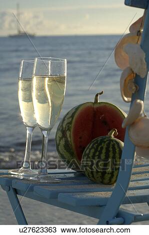 Stock Image - A bottle of sparkling wine on a chair at the beach. Fotosearch