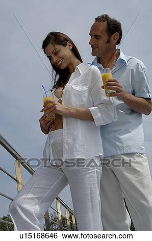 Stock Photograph - A couple dressed in white is enjoying a drink. Fotosearch