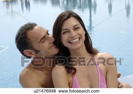 A couple sitting close together - at the swimming pool View Large Photo Image Stock Photo - A couple sitting close together - at the swimming pool. Fotosearch