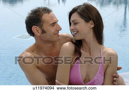 A couple sitting close together at the swimming pool View Large Photo Image Picture - A couple sitting close together at the swimming pool. Fotosearch