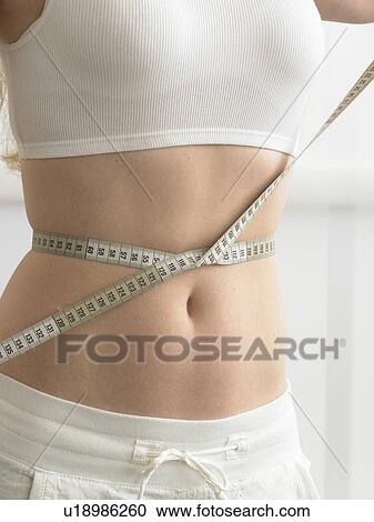 A measuring tape is twined around a woman' s belly View Large Photo Image Stock Image - A measuring tape is twined around a woman' s belly. Fotosearch