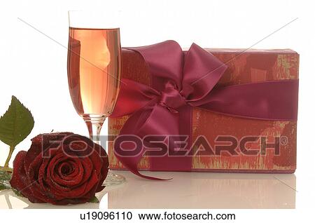Stock Image - Arrangement of gifts, rose and glass of sparkling wine. Fotosearch
