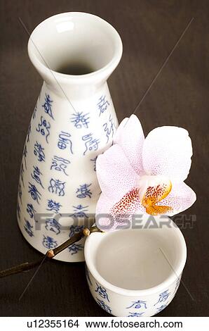 Picture - Asian crockey with blue characters and orchid blossom. Fotosearch
