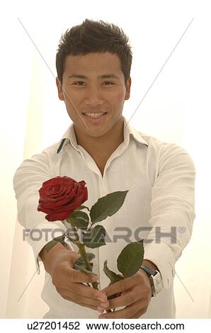 Stock Image - Asian man with a red rose and kissmouth on his check. Fotosearch