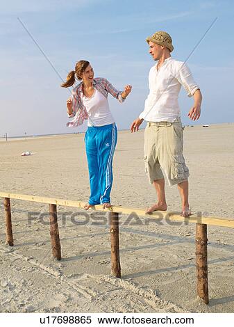 Stock Photography - Balancing couple on the beach. Fotosearch
