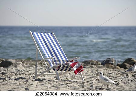 Picture - Blue and white deckchair on the beach. Fotosearch