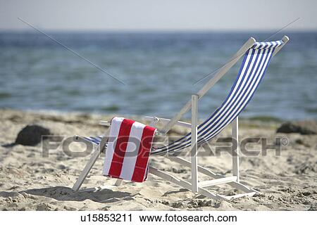 Stock Image - Blue and white deckchair on the beach. Fotosearch