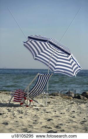 Stock Photography - Blue and white sunshade and deckchair on the beach. Fotosearch