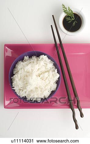 Stock Image - Bowl of rice, chopsticks and sauce. Fotosearch