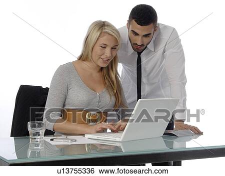 Stock Photograph - Businessman and woman with laptop at desk. Fotosearch