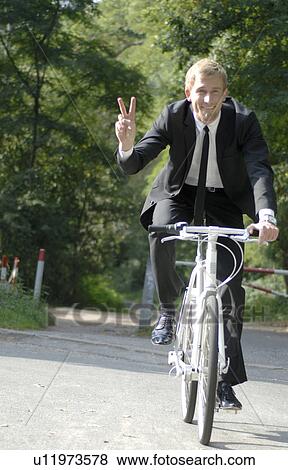 Stock Photo - Businessman biking through the forest. Fotosearch