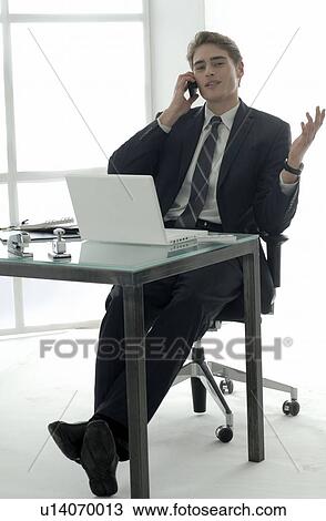 Stock Image - Businessman on the phone at desk with laptop. Fotosearch