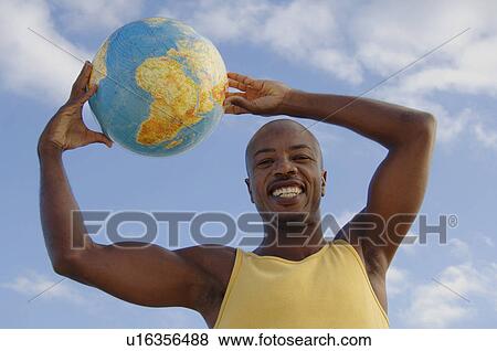 Stock Photo - Coloured man holding a globe over his head. Fotosearch