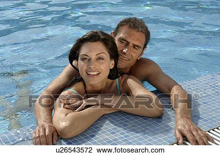 Stock Image - Couple at pool edge. Fotosearch
