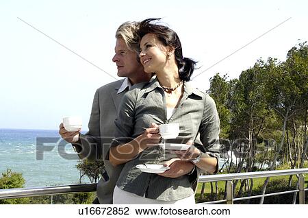 Couple at the sea is drinking coffee View Large Photo Image Stock Image - Couple at the sea is drinking coffee. Fotosearch