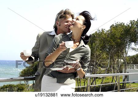Stock Image - Couple at the sea is drinking coffee. Fotosearch