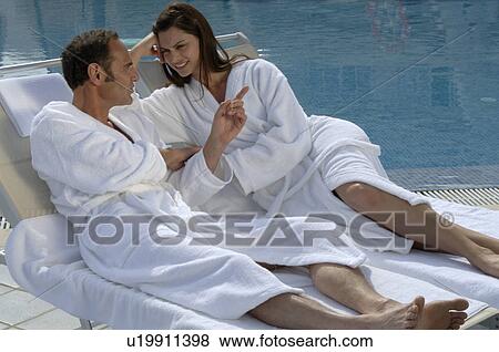 Stock Photo - Couple in bathrobes at the swimming pool. Fotosearch