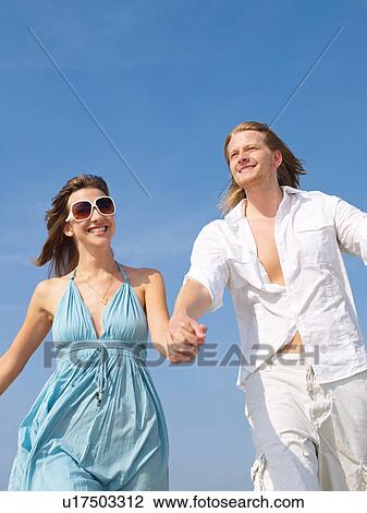 Couple walking hand in hand on the beach View Large Photo Image Stock Image - Couple walking hand in hand on the beach. Fotosearch