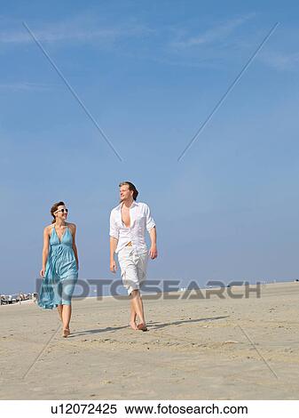Stock Photography - Couple walking hand in hand on the beach. Fotosearch