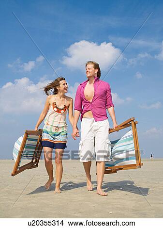 Couple with beach loungers View Large Photo Image Picture - Couple with beach loungers. Fotosearch