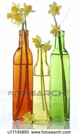 Stock Image - daffodils in coloured glass bottles. Fotosearch