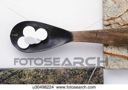 Picture - Dr. Schüssler's cell salts pills in a wooden spoon. Fotosearch