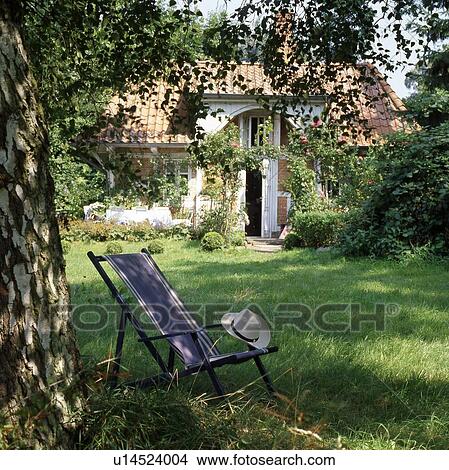 Picture - Empty deckchair with hat in garden. Fotosearch