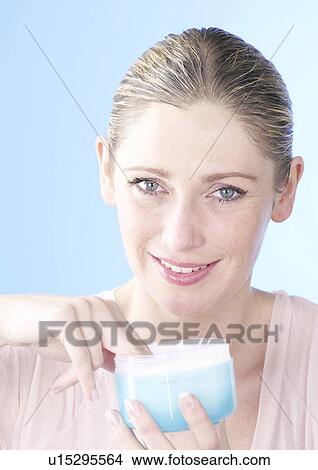 Picture - Fair haired woman grasping into cream pot. Fotosearch