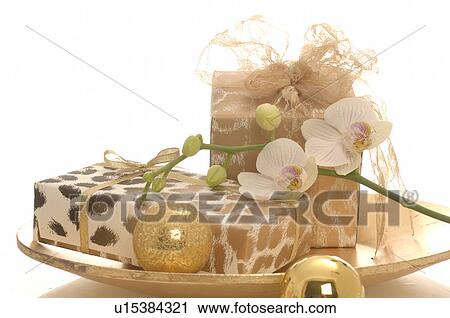 Stock Image - Gifts on a plate decorated with christmas balls and orichd blossoms. Fotosearch