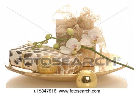 Stock Photograph - Gifts on a plate decorated with christmas balls and orichd blossoms. Fotosearch