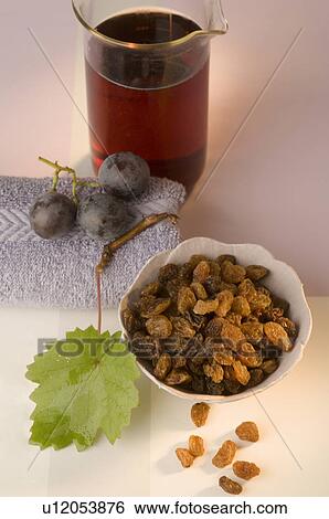 Stock Photograph - Glas mit Traubenkernöl aus roten Trauben und Rosinen in einer weißen Schüssel. Fotosearch