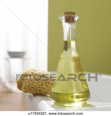 Stock Image - Grapeseed oil and sponge on the bathtub border. Fotosearch