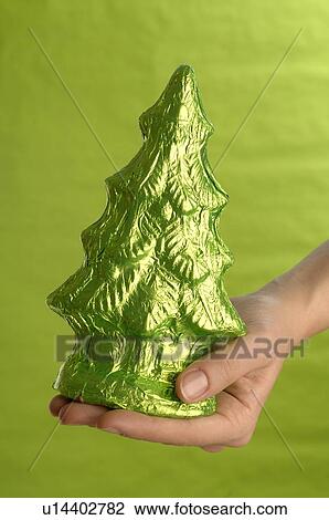 Stock Image - Hand holding chocolate Christmas tree. Fotosearch