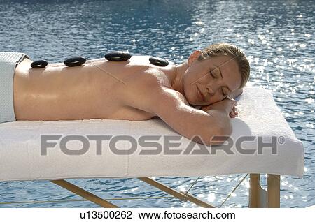 Stock Image - Hot stone massage - woman on the massagebed. Fotosearch